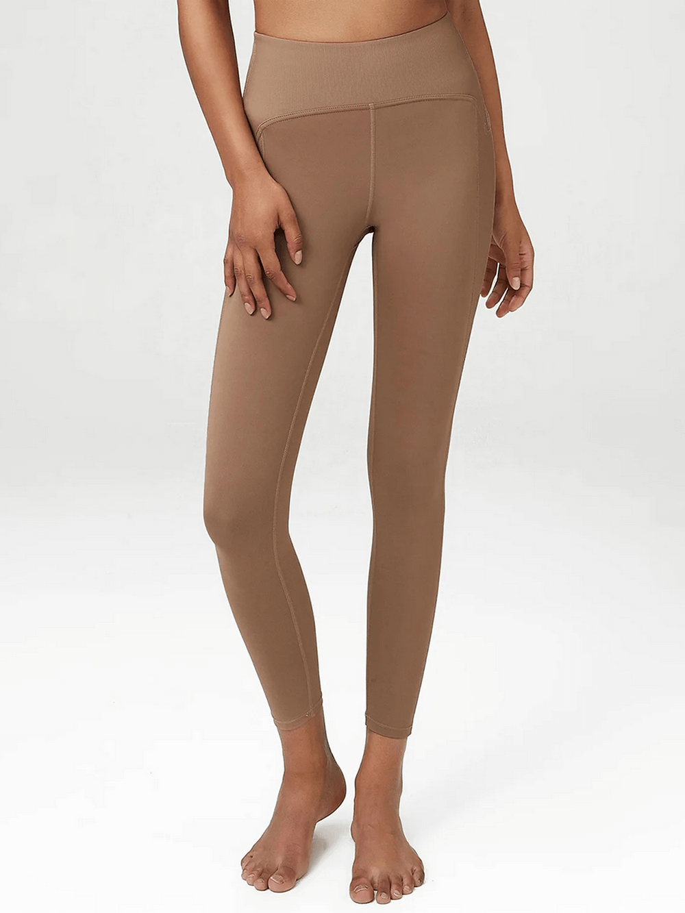 Woman wearing beige yoga leggings with elastic waistband for perfect fit during workouts like yoga, running, and dancing.